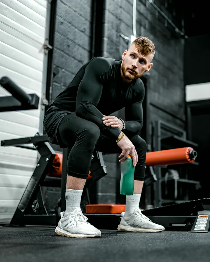 Coach Jordan Ellis sitting on a bench on the strength floor