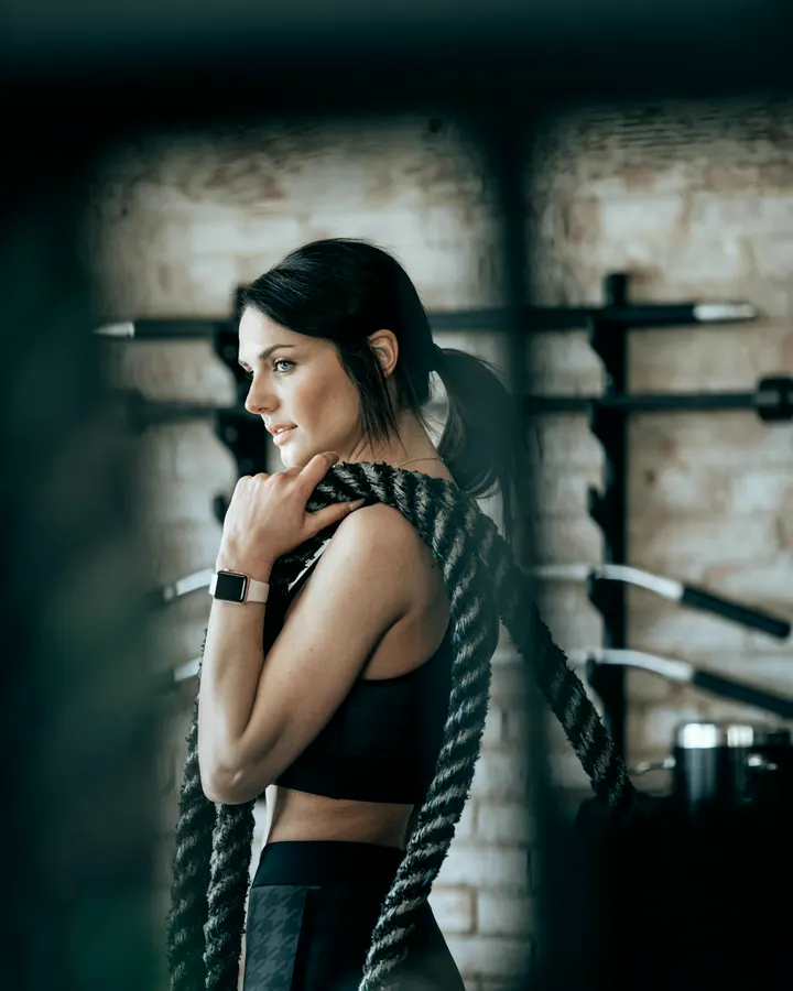 Coach Maya Reyes holding a battle rope over one shoulder
