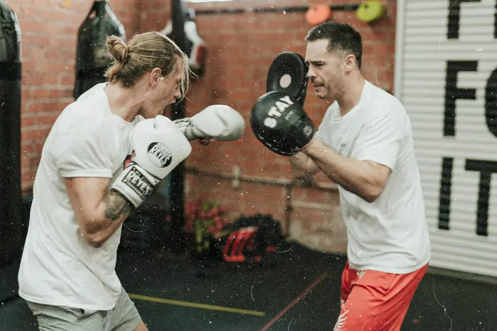 A coach holding pads for a member during a boxing session